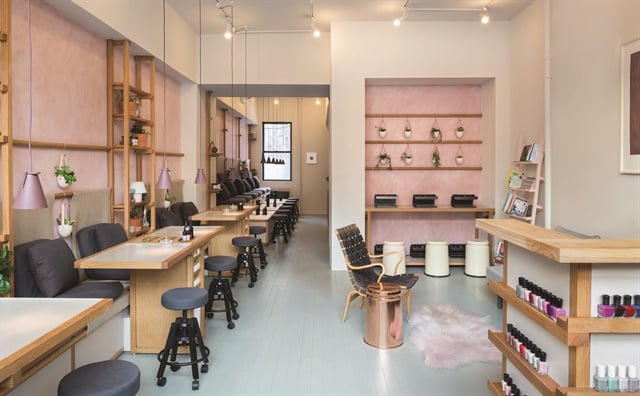 The salon interior hosts an abundance of plants and fresh flowers along the sides of each station, and a rack of thought-provoking books.