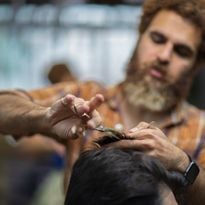 A barber inside his shop works on a client.